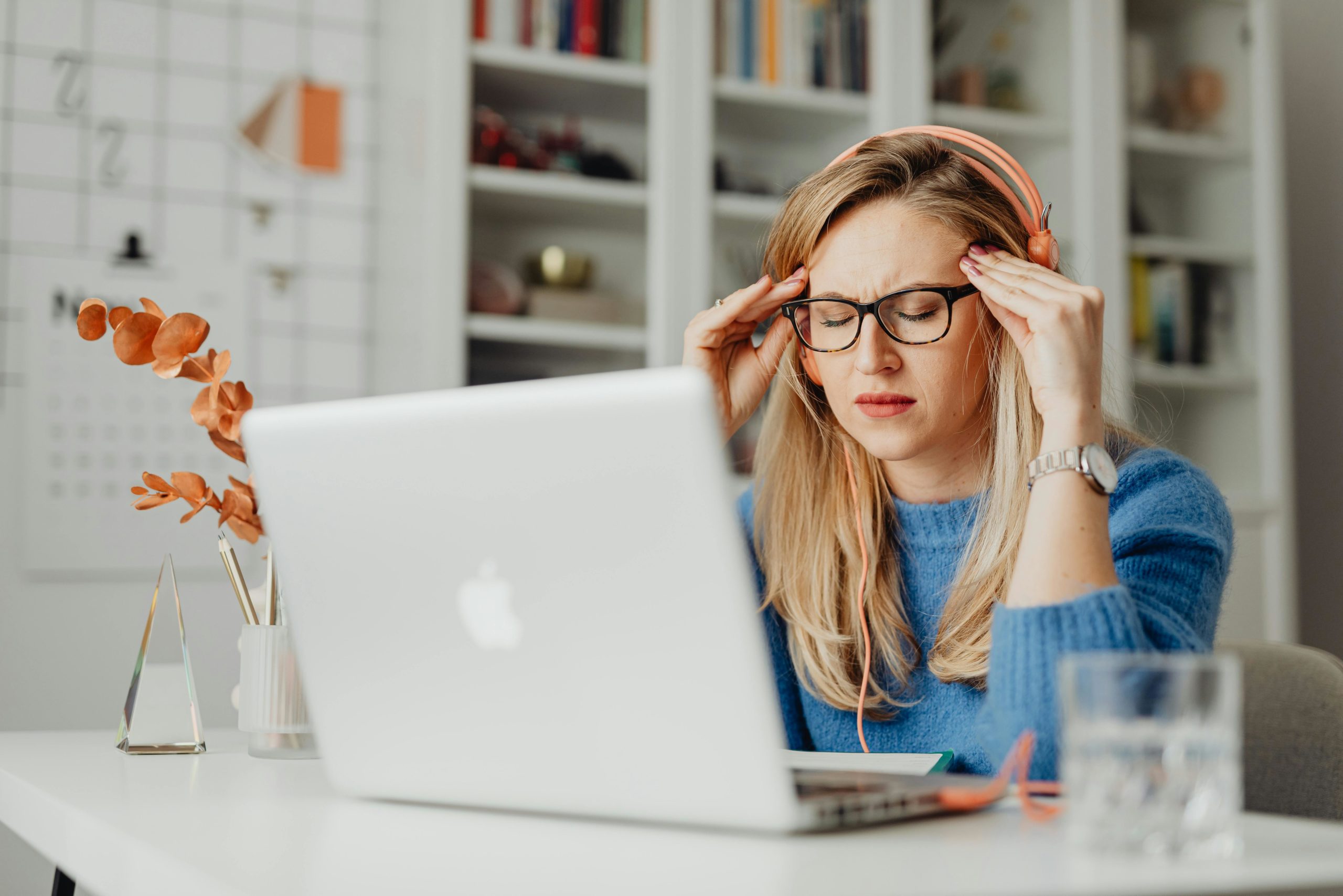 A woman experiencing stress while working on a laptop in a home office setting, highlighting a work-from-home lifestyle.